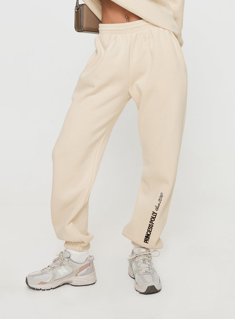 back view of model wearing Princess Polly Princess Polly Track Pants Block / Cursive Text Stone Mid Rise 